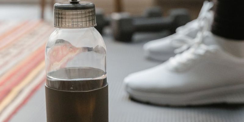 A bottle of water next to a rolled-up exercise mat.